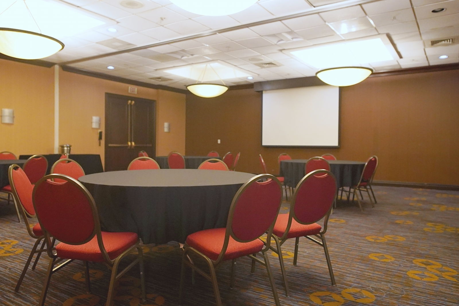 The meeting space set with banquet rounds and a projection screen