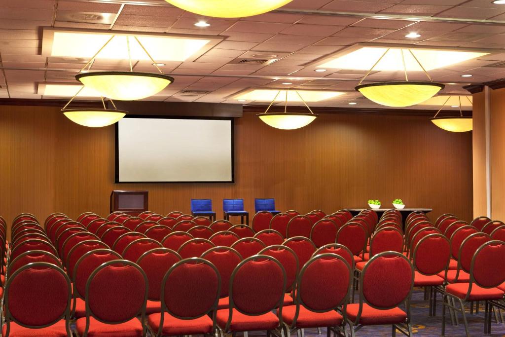 The full room undivided and set theatre-style, rows of chairs facing a projection screen and lectern
