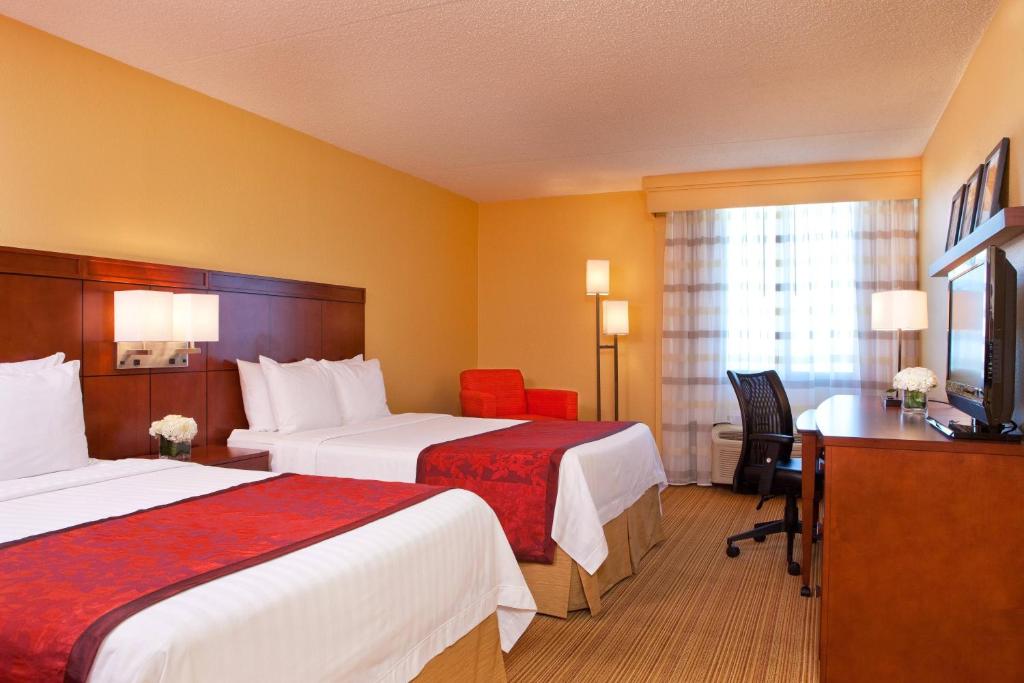 Guest room with two queen beds, desk and armchair